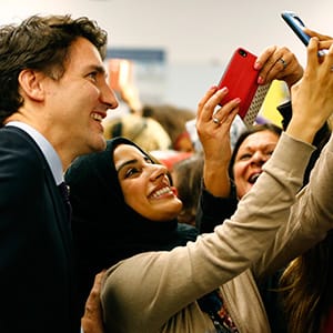 Canada's Prime Minister Justin Trudeau (L) poses with airport staff as they await Syrian refugees to arrive at the Toronto Pearson International Airport in Mississauga, Ontario, December 10, 2015. After months of promises and weeks of preparation, the first planeload of Syrian refugees was headed to Canada on Thursday, aboard a military plane to be met at Toronto's airport by Trudeau. (Mark Blinch/Reuters)