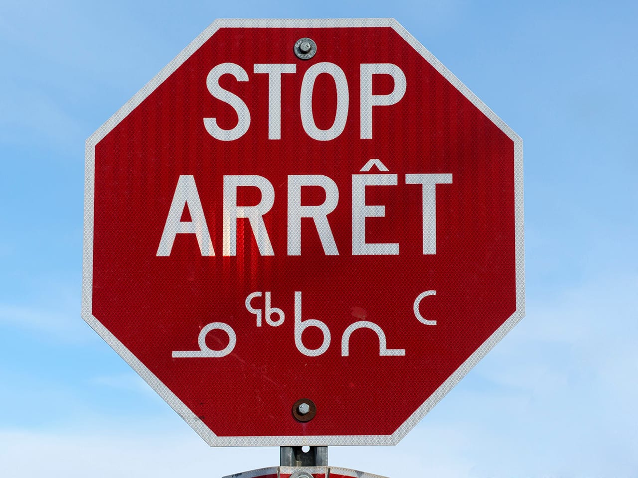 Stop sign in downtown Iqaluit, in 3 languages (English, French & Inuktitut).