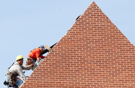 Builders work on the roof of a new housing construction site in Alexandria