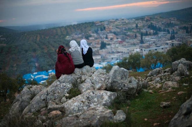 Three young residents of a Syrian refugee camp overlook the town of Qah, Syria. (Daniel Leal-Olivas/i-Images/Polaris).