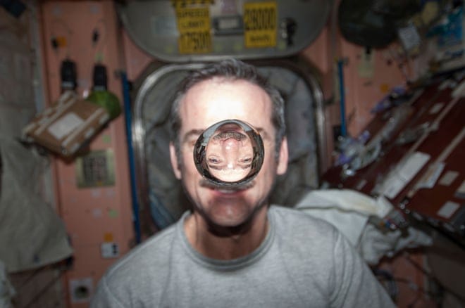 Canadian Space Agency astronaut Chris Hadfield, Expedition 34 flight engineer, watches a water bubble float freely between him and the camera, showing his image refracted, in the Unity node of the International Space Station in 2013. (REUTERS/NASA/Handout)