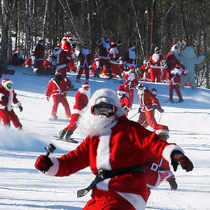 Skiers and snowboarders dressed as Santa participate in a charity run down a slope at Sunday River Ski Resort in Newry