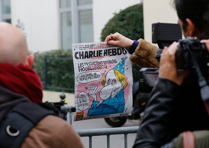 A man holds up the front page of the latest issue of Charlie Hebdo, a satirical magazine, which shows a caricature of French author Michel Houellebecq. At least 12 have died in a shooting at the Charlie Hebdo offices. (Jacky Naegelen/Reuters)