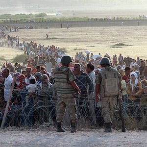 Turkish soldiers stand guard as Syrians wait behind the border fences near the southeastern town of Suruc in Sanliurfa province