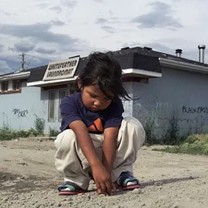 Pikangikum_SadGirl50-07/24/01-A sad young girl plays by herself on a dusty road in Pikangikum. Pikan