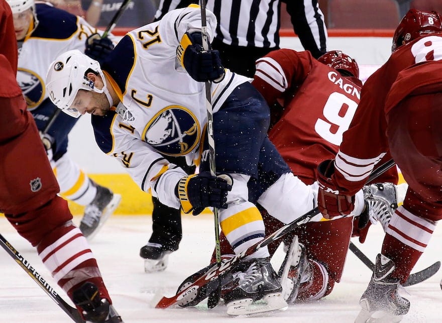 Buffalo Sabres' Brian Gionta (12) trips over Arizona Coyotes' Sam Gagner (9) and Tobias Rieder (8), of Germany, during the third period of an NHL hockey game Monday, March 30, 2015, in Glendale, Ariz. (AP Photo/Ross D. Franklin)