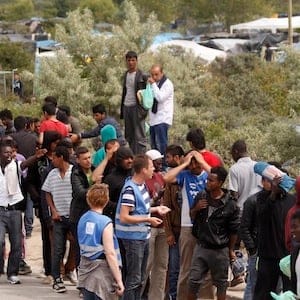 Migrants queue to receive their daily food distribution in a makeshift camp known as the "jungle", in Calais, northern France, Thursday, June 25, 2015. Migrants from Sudan, Eritrea and elsewhere are camped by the thousand in the port city of Calais trying to reach Britain, where they believe they will have better job prospects. (AP Photo/Michel Spingler)