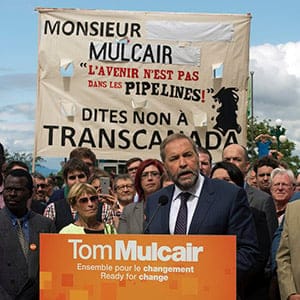 Protesters hold up an anti-pipeline banner as Federal NDP Leader Tom Mulcair speaks to supporters at a rally Wednesday, August 12, 2015 in Quebec City, Que. (Ryan Remiorz/CP)