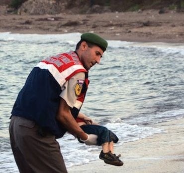 A paramilitary police officer carries the lifeless body of a migrant child after a number of migrants died and a smaller number were reported missing after boats carrying them to the Greek island of Kos capsized, near the Turkish resort of Bodrum early Wednesday, Sept. 2, 2015. (AP Photo/DHA) TURKEY OUT