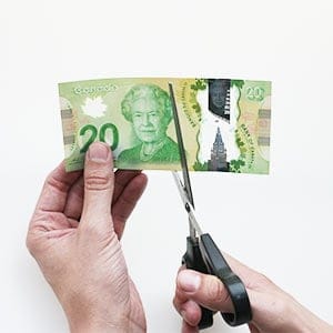 Man cutting a $20 bill in half. Photograph by May Truong