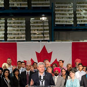 Surrounded by racks of food, Conservative leader Stephen Harper speaks about the Syrian refugee crisis during a campaign event in Surrey, B.C., Thursday September 3, 2015. (Adrian Wyld/CP)
