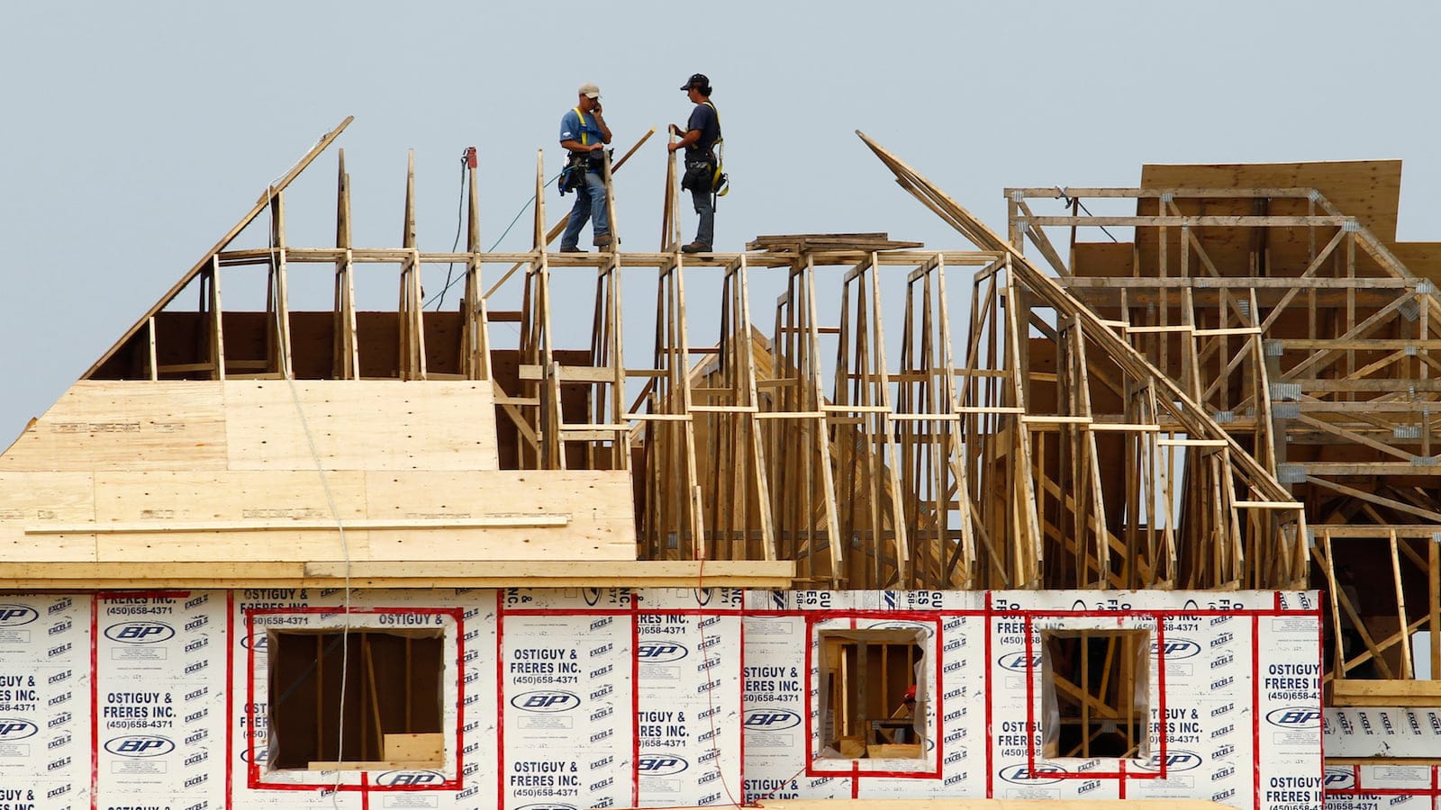 Builders work on the the roof of a new home under construction in the Montreal suburb of Brossard, August 10, 2010. Canadian housing starts fell in July for a third straight month and new home prices rose less than expected in June, further evidence that the housing boom that helped drive the country's recovery from recession is starting to stall. REUTERS/Shaun Best (CANADA - Tags: BUSINESS) - RTR2H7WP