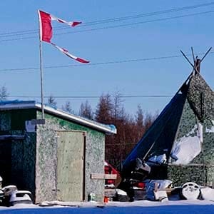 The remains of a Canadian flag can be seen flying over a building in Attawapiskat, Ont. on November 29, 2011. The federal government is forcing the troubled Attawapiskat First Nation to pay a private-sector consultant about $1,300 a day to run its finances - even though the government's own assessments say the third-party management system is not cost-effective. (Adrian Wyld/CP)