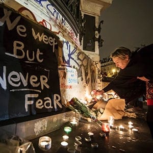 epa05025423 People place flowers and light candles in tribute for the victims of the 13 November Paris attacks at the foot of the statue on Place de la Republique in Paris, France, 14 November 2015. At least 120 people have been killed in a series of attacks in Paris on 13 November, according to French officials. (IAN LANGSDON/EPA/CP)
