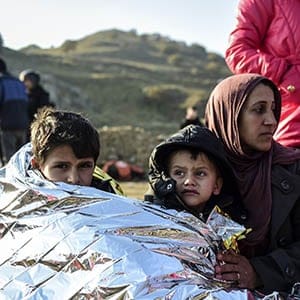 A Syrian family waits after arriving on the Greek island of Lesbos along with other migrants and refugees, on November 17, 2015, after crossing the Aegean Sea from Turkey. At least eight people drowned when a boat carrying migrants from Turkey sank off the Greek island of Kos, the coastguard said on November 17, 2015. They were the latest of nearly 3,500 deaths at sea this year among people making desperate bids to flee war and poverty and to reach Europe, according to UN figures. European leaders tried to focus on joint action with Africa to tackle the migration crisis, as Slovenia became the latest EU member to act on its own by barricading its border. AFP PHOTO/BULENT KILIC (Photo credit should read BULENT KILIC/AFP/Getty Images)