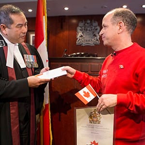 Dror Bar-Natan (right) hands a letter to Judge Albert Wong to disavow the portion of the oath that pertains to the Queen following a citizenship ceremony in Toronto on Monday November 30, 2015. THE CANADIAN PRESS/Chris Young