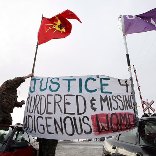 Native protesters rise a banner during a blockade at the VIA train tracks and Wyman's Road near Shannonville, Ont., on Wednesday March 19, 2014. The protesters want justice for murdered and missing indigenous women. Lars Hagberg/CP
