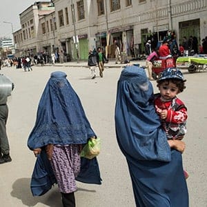 Afghanistan, Kabul, March 27, 2015. Burqa-clad women walk past Afghan riot police next to the Kabul river close to the spot where last week the 27-year old woman Farkhunda was murdered by a mob after she was falsely accused of burning a Koran. The police is expecting demonstration to ask for justice of the killers. (Joel van Houdt)