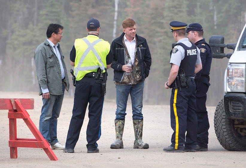 Alberta Wildrose Leader Brian Jean, centre, talkswith police near a wildfire in Fort McMurray, Alta., on Thursday, May 5, 2016. Jean's house was burned down in the fire. (Jason Franson/CP)