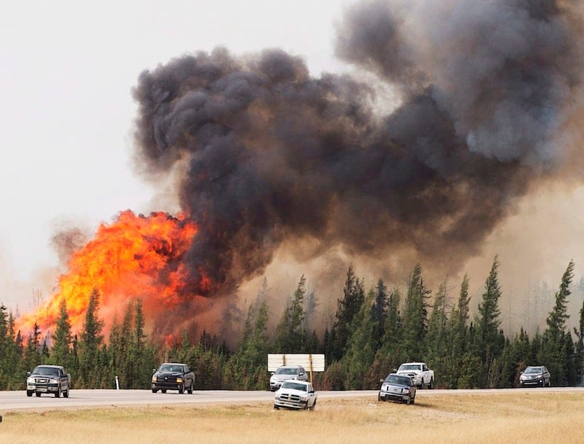A convoy of evacuees from Fort McMurray, Alberta drive past wildfires that are still burning out of control as they leave the city Saturday, May 7, 2016. (Ryan Remiorz/CP)