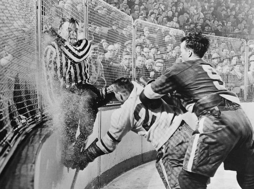 (Original Caption) Frank Udvari, tries to get out of harm's way as Red Wing Gordie Howe (right) sends Toronto's Gordie Hannigan into the boards during semifinal Stanley Cup playoffs. Detroit won this game, 3-2. (Bettmann/Getty Images)