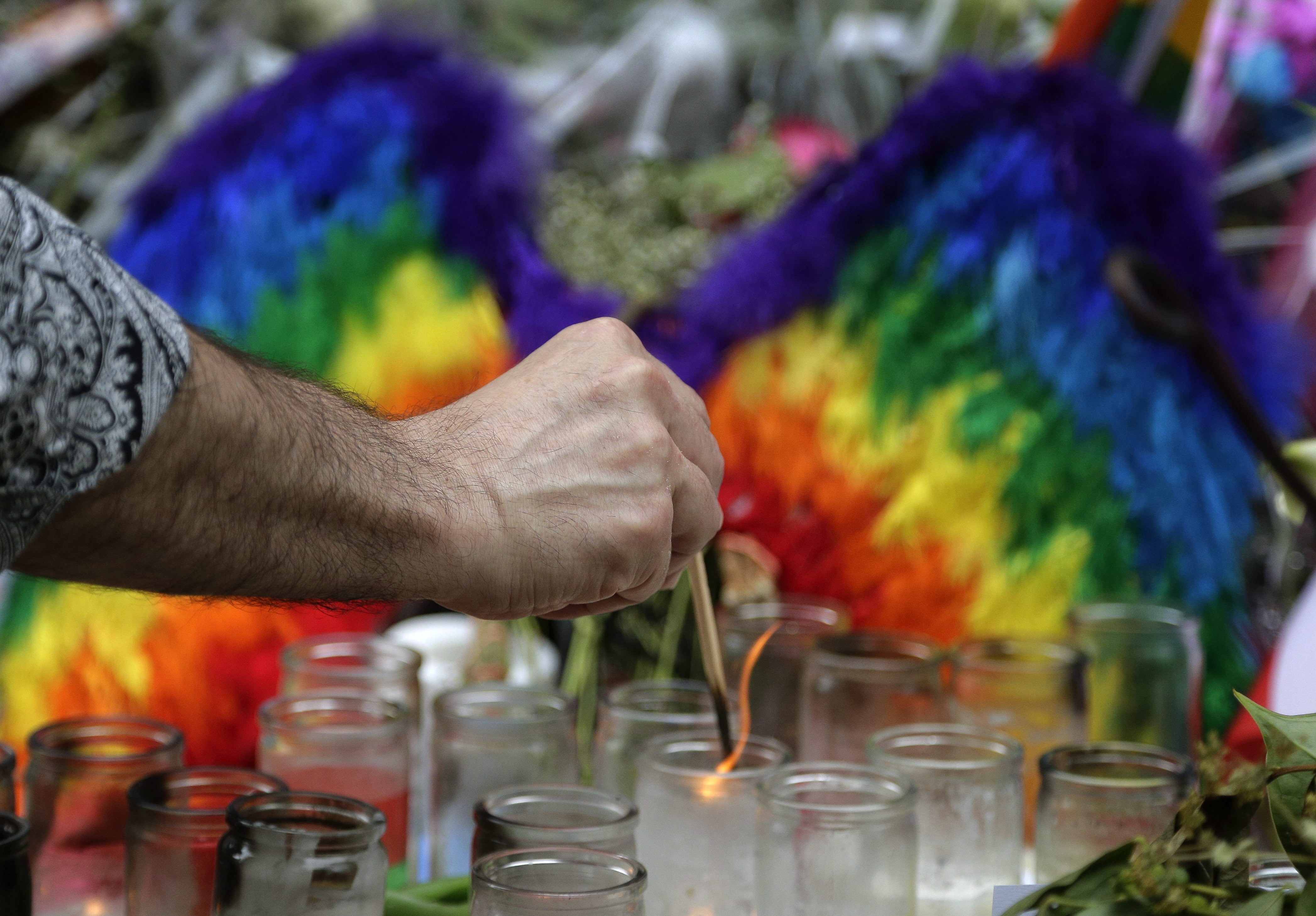 A man lights candles on a memorial outside the Stonewall Inn for victims of the Orlando Shooting, Thursday, June 16, 2016, in New York. Members of the United Nations' LGBT Core Group met at the bar on Thursday. (AP Photo/Julie Jacobson)