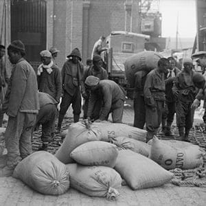Men of Chinese Labour Corps loading sacks of oats on to a lorry at Boulogne, 12th August 1917. (Lieutenant Ernest Brooks/Imperial War Museums)