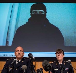 Video footage showing Aaron Driver is seen behind RCMP Deputy Commissioner Mike Cabana (left) and Assistant Commissioner Jennifer Strachan during a press conference for what the RCMP are calling a terrorism incident, in Strathroy, Ontario yesterday, on Thursday, Aug. 11, 2016 in Ottawa. THE CANADIAN PRESS/Justin Tang
