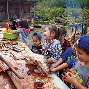 Ms. Wilson's Grade 1 class takes part in Salmon Week events (2015), learning how to prepare salmon for traditional barbecue around the fire. During Salmon Week, our students get hands-on experience with smoking, barbecuing, drying and jarring salmon. (Johanna Gordon-Walker)