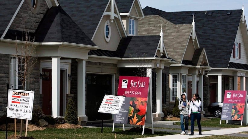 People walk past new homes that are for sale in Oakville, Ont. THE CANADIAN PRESS/Nathan Denette