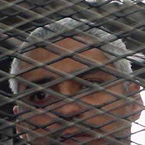 Al Jazeera journalist Mohammed Fahmy stands behind bars at a court in Cairo May 15, 2014. (Reuters)