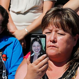 Bernice Catcheway holds a phone with a photo of her daughter Jennifer who went missing 6 years ago at an unveiling ceremony of a monument honouring Manitoba's missing and murdered women and girls in Winnipeg, Tuesday, August 12, 2014. (John Woods/CP)