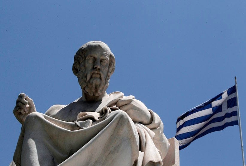 The marble statue of the ancient Greek philosopher Plato stands in front of the Athens Academy, as the Greek flag flies in Athens on Tuesday June 5, 2012. (AP Photo/Dimitri Messinis)