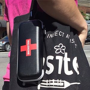A woman carries a naloxone kit and a bag from Insite, the safe injection site, while walking in the Downtown Eastside of Vancouver, B.C., on Wednesday July 27, 2016. Naloxone is used to reverse the effects of overdoses in drug users who have taken opioids. The provincial government has announced the creation of a joint task force on overdose response. (Darryl Dyck/CP)