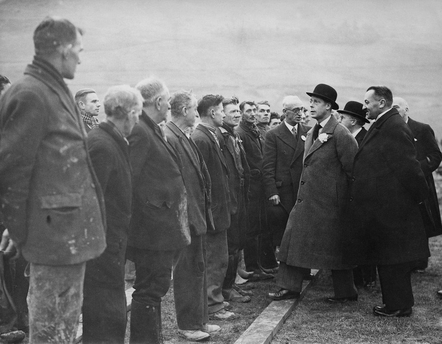 King Edward VIII, Duke of Windsor (1894-1972, in bowler hat, right) speaking to a group of unemployed men at the Glebe Sports Ground at Abertillery, South Wales, 19th November 1936. The men built the ground on the site of a dump over a period of two years. (Photo by Popperfoto/Getty Images)