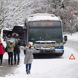 People throw snowballs as a bus is stuck on the road in North Vancouver, B.C., Friday, Feb. 3, 2017. A snowstorm hit the northshore leaving cars and trucks slipping and sliding. (Jonathan Hayward/CP)