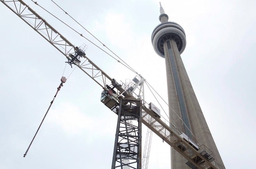 A construction crane stand in front of the CN tower in downtown Toronto on Saturday, February 4, 2012. The condo explosion is changing the shape and culture of Canada's cities. THE CANADIAN PRESS/Pawel Dwulit