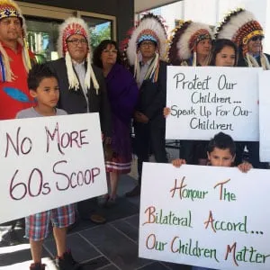 Children hold signs along with members of the Saskatoon Tribal Council outside of the courthouse in Regina Sask., on Tuesday, June 28, 2016. The Saskatchewan government is seeking an injunction to take back responsibility for children under the care of the Saskatoon Tribal Council, but some say the move infringes on aboriginal sovereignty. (Jennifer Graham/CP)