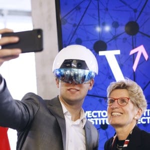 Kathleen Wynne, premier of Ontario, right, poses for a selfie photograph with a man wearing a virtual reality (VR) helmet in the Vector Institute at the MaRS Discovery District in Toronto, Ontario, Canada, on Thursday, March 30, 2017. A new institute for artificial intelligence research opened Thursday with funding from the federal and Ontario governments as well as the private sector. The Vector Institute will specialize in the fields of machine learning and deep learning, which uses software and algorithms to simulate the neural circuits of the human brain. (Cole Burston/Bloomberg/Getty Images)