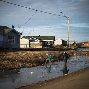 Indigenous children play in a water- filled ditch in the northern Ontario First Nations reserve in Attawapiskat, Ont., on Tuesday, April 19, 2016. In many ways, Attawapiskat - population 2,100 - has all the trappings of any small town, including older folk lamenting the changing of the times. (Nathan Denette/CP)