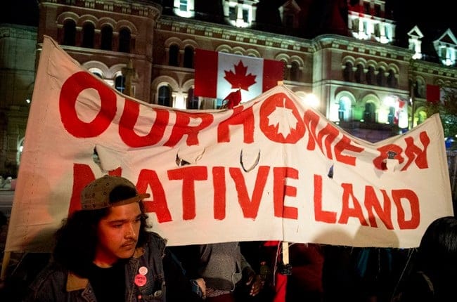 People hold up a sign during a demonstration on Parliament Hill, as a crowd gathered to erect a teepee as part of a four-day Canada Day protest, in Ottawa on Thursday, June 29, 2017. THE CANADIAN PRESS/Justin Tang