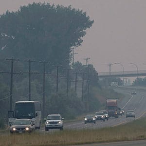 Cars and trucks drive though the thick smoke caused by wildfires just outside of Kamloops, B.C., on Sunday, July 16, 2017. Over a hundred wildfires are burning throughout British Columbia, forcing thousands of residents to be evacuated or placed on evacuation alert. (Jonathan Hayward/CP)