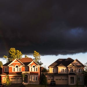 Ontario, Canada - July 1, 2016: The new houses are under rainbow. there is a big black clouds under the sky in shine of sunset.