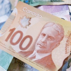 The days of paper money are fast ending. The new Canadian polymer 100 dollar bill atop a pile of the old paper bills.