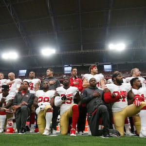 PHOENIX, AZ - OCTOBER 1: The San Francisco 49ers kneel and stand in solidarity on the sideline, during the anthem, prior to the game against the Arizona Cardinals at the University of Phoenix Stadium on October 1, 2017 in Phoenix, Arizona. The Cardinals defeated the 49ers 18-15. (Photo by Michael Zagaris/San Francisco 49ers/Getty Images) *** Local Caption ***