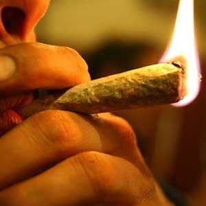 Marihuana joint on fire, in the lips