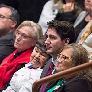 Prime Minister Justin Trudeau sits in the crowd before he delivered an apology on behalf of the Government of Canada to former students of the Newfoundland and Labrador Residential Schools in Happy Valley-Goose Bay, N.L. on Friday, Nov. 24, 2017. THE CANADIAN PRESS/Andrew Vaughan
