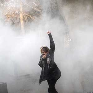 TOPSHOT - An Iranian woman raises her fist amid the smoke of tear gas at the University of Tehran during a protest driven by anger over economic problems, in the capital Tehran on December 30, 2017.
Students protested in a third day of demonstrations sparked by anger over Iran's economic problems, videos on social media showed, but were outnumbered by counter-demonstrators. / AFP PHOTO / STR (Photo credit should read STR/AFP/Getty Images)