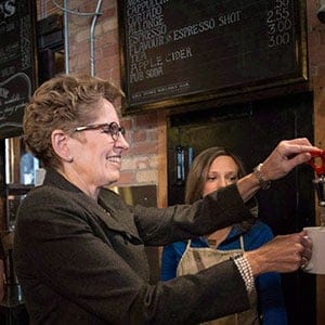 Ontario Premier Kathleen Wynne makes herself a cup of tea at a Toronto coffee shop, before making an announcement regarding the minimum wage in the province, on Thursday, January 30, 2014. Ontario's minimum wage workers are set to get a bump in their paycheques after the province voted in favour of raising the standard to $15 an hour over the next two years. (Chris Young/CP)
