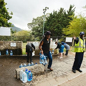 A security officer directs residents as they fill water bottles and containers at the Newlands natural water spring in Cape Town, South Africa on Monday, Nov. 13, 2017. Cape Town has tightened water usage restrictions, banning the use of potable water to irrigate gardens, wash cars or top up swimming pools, as it confronts its worst drought on record and a delay to the onset of the winter rainy season. (Waldo Swiegers/Bloomberg/Getty Images)